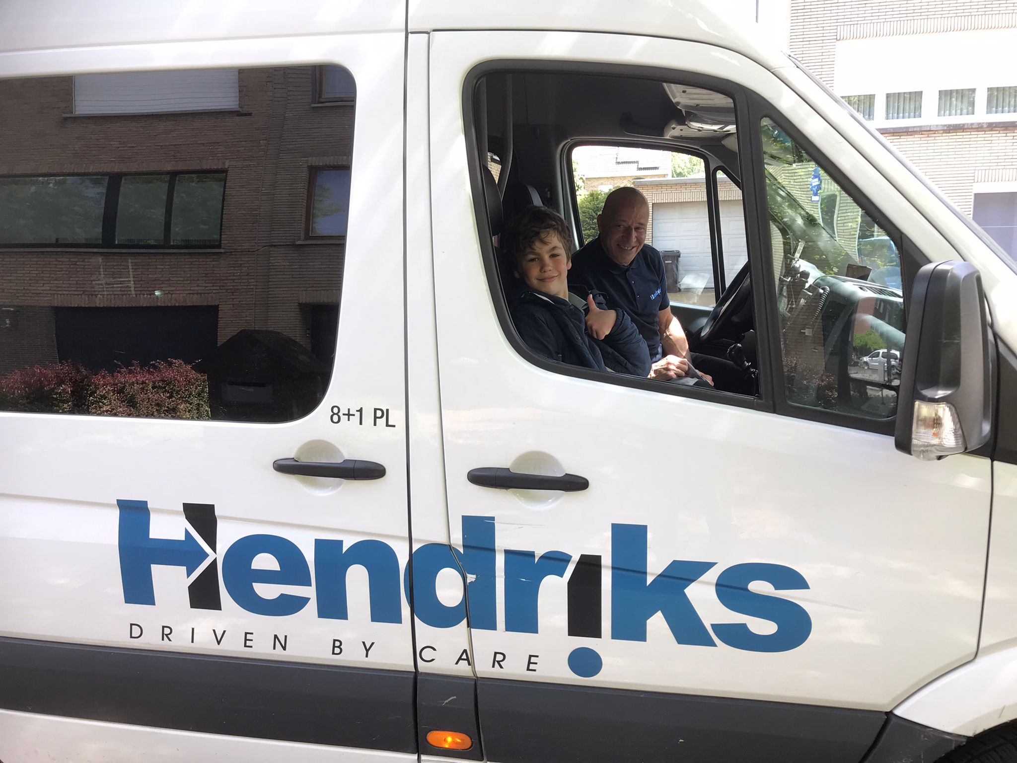 Een foto waarop je een leerling en een taxichauffeur in een minibusje ziet